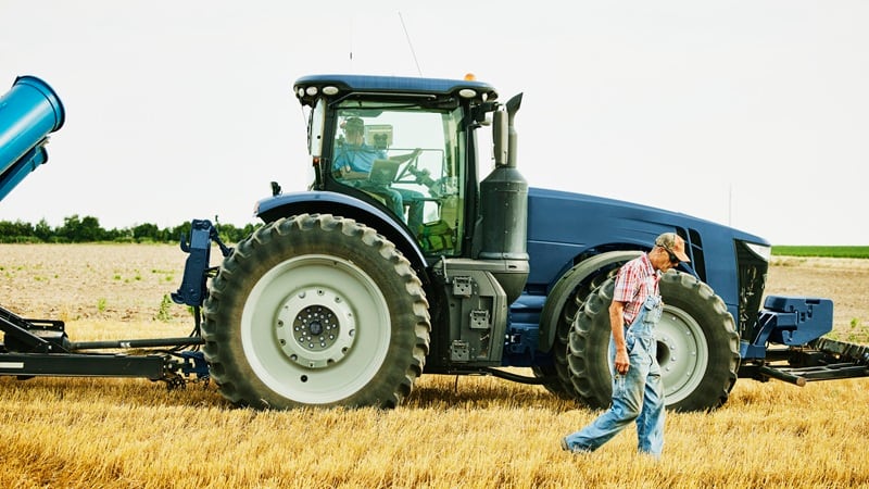 A farmer walking in front of a tractor