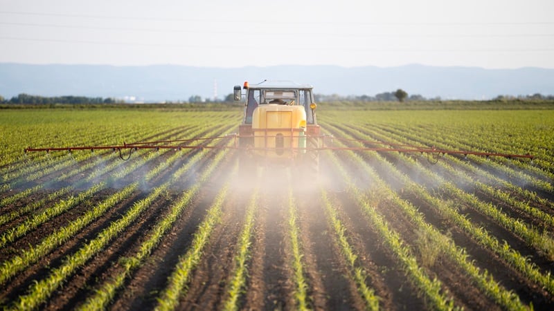 A tractor spraying fertilizer on a field